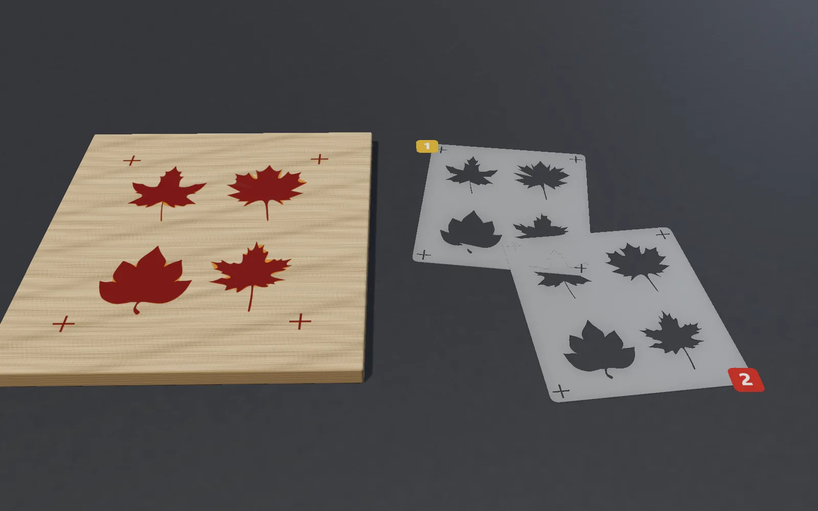 A two-colour stencil job: maple leaves painted on wood in yellow then red, and the two PET stencils numbered 1 and 2 with registration crosses in the corners